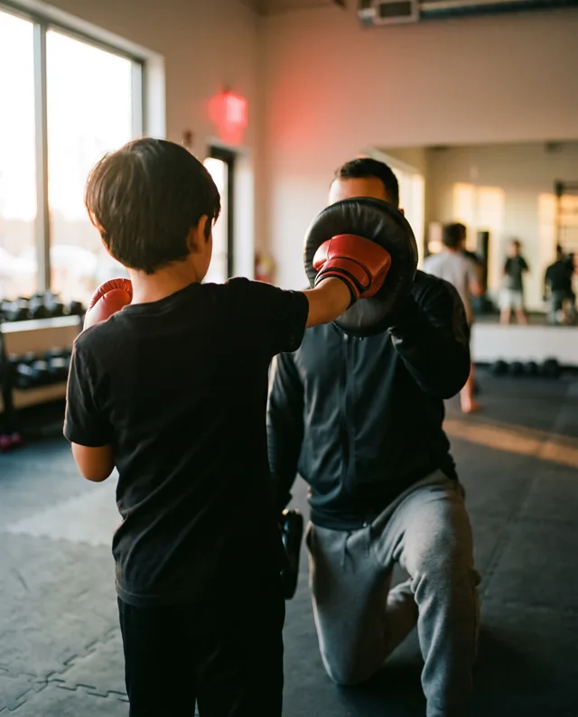 A young student punching a pad held by a coach
