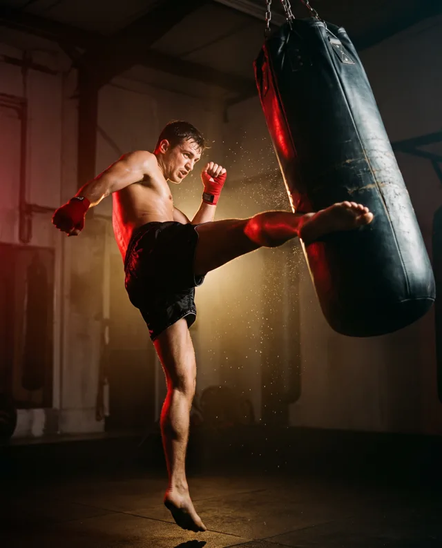 A Muay Thai fighter kicking a heavy bag